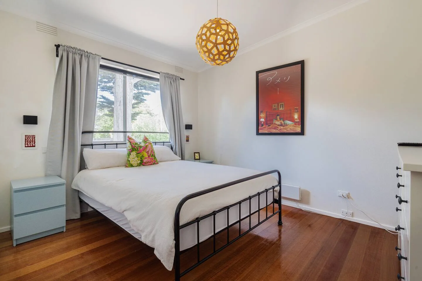 Un dormitorio con una cama junto a una gran ventana con cortinas.