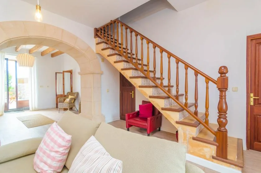 A bright living room with seating beneath a wooden staircase.