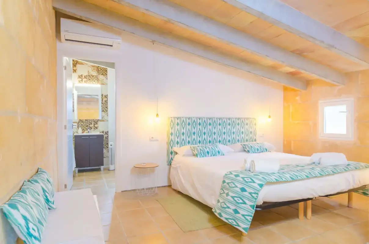 A bedroom with beds, patterned bedding, and exposed wooden ceiling beams.