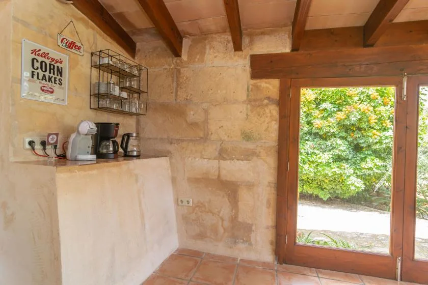 A small kitchen nook with a counter, coffee appliances, and a glass door.