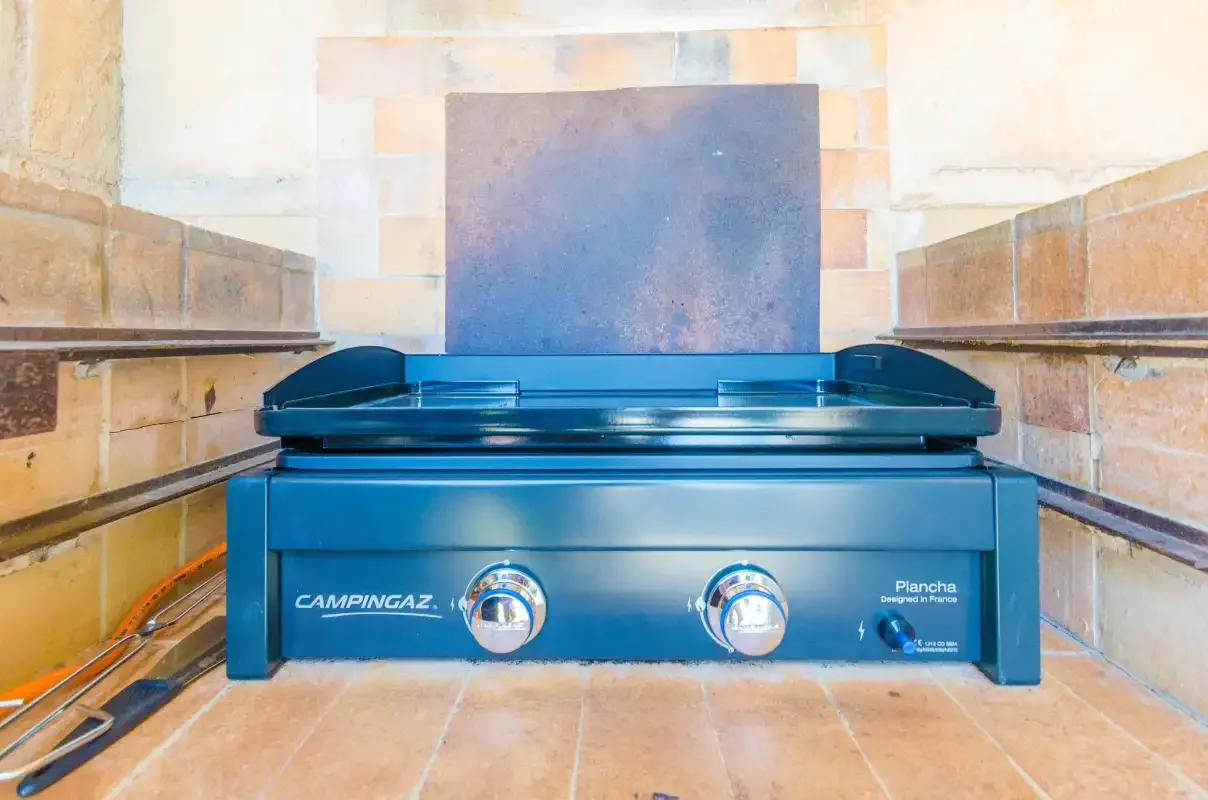 A tabletop gas grill sits in a tiled cooking alcove.