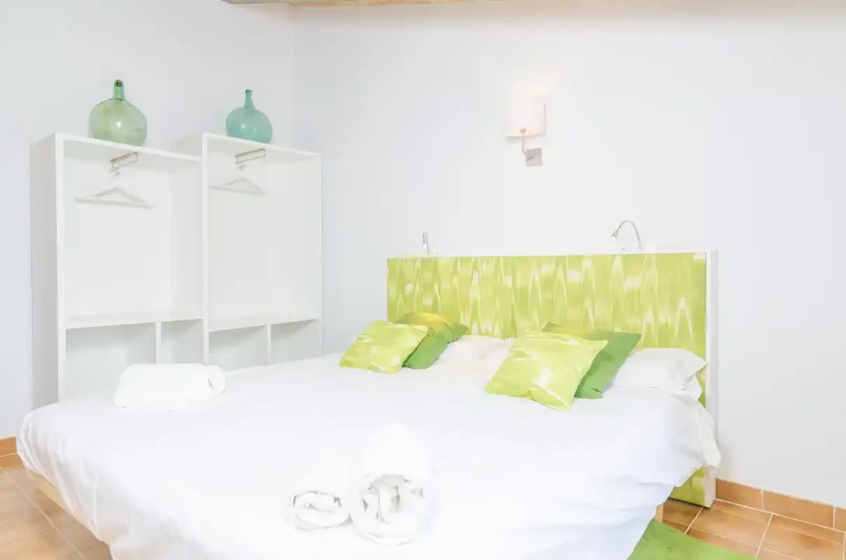 A bright bedroom with a large bed and green accents.