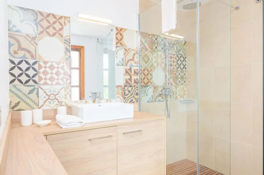 A bright bathroom with a sink vanity and patterned tile accents.