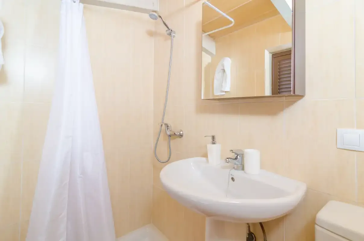 A bathroom with a sink, mirror, and shower.