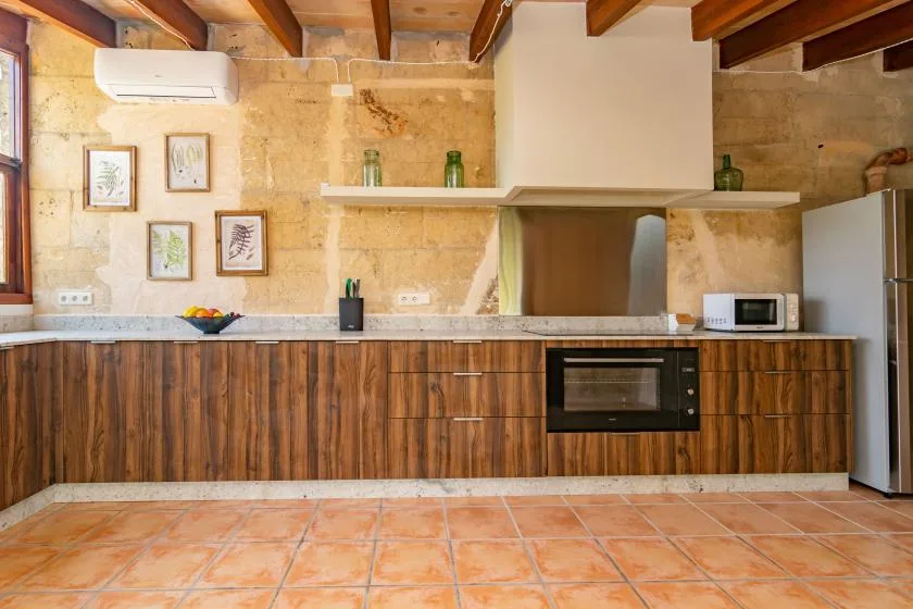 A kitchen with wood-fronted cabinets, a countertop, and exposed ceiling beams.