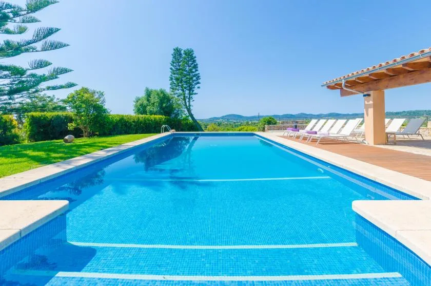 An outdoor swimming pool sits beside a row of lounge chairs.