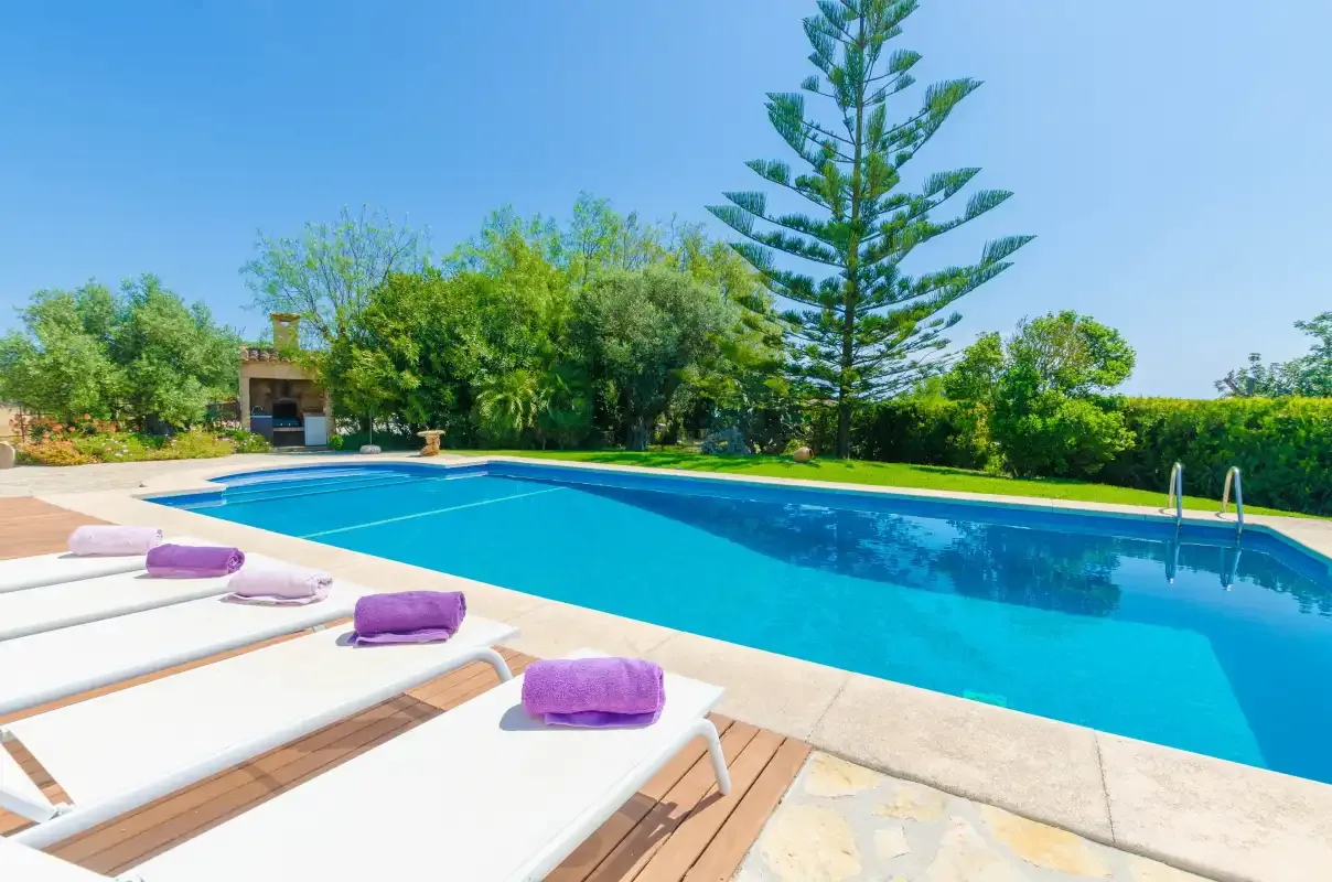 Outdoor swimming pool beside a sunny deck with loungers.