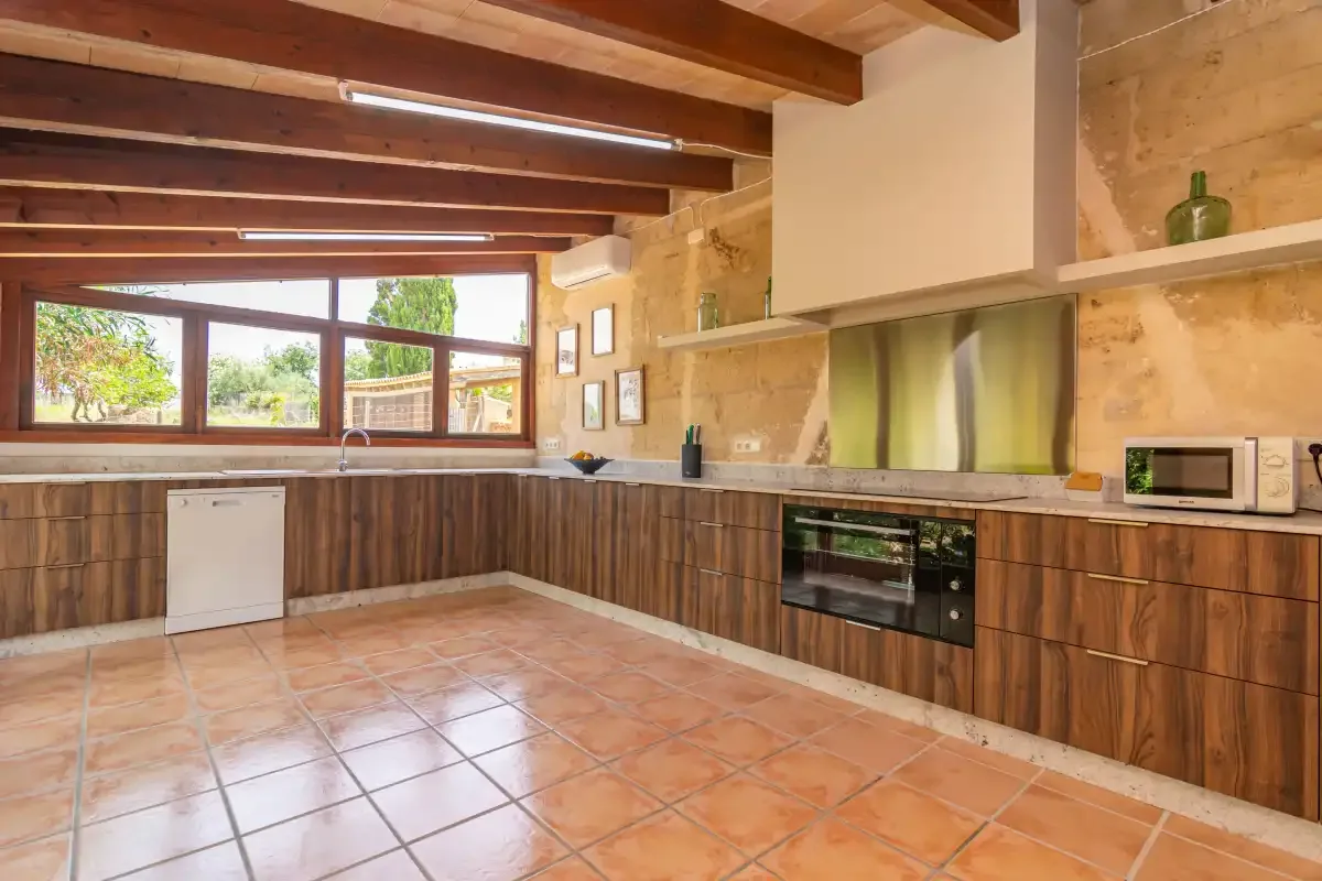 A rustic kitchen with wooden cabinets and a wide window.