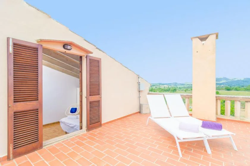 A tiled outdoor terrace with lounge seating beside an open doorway.