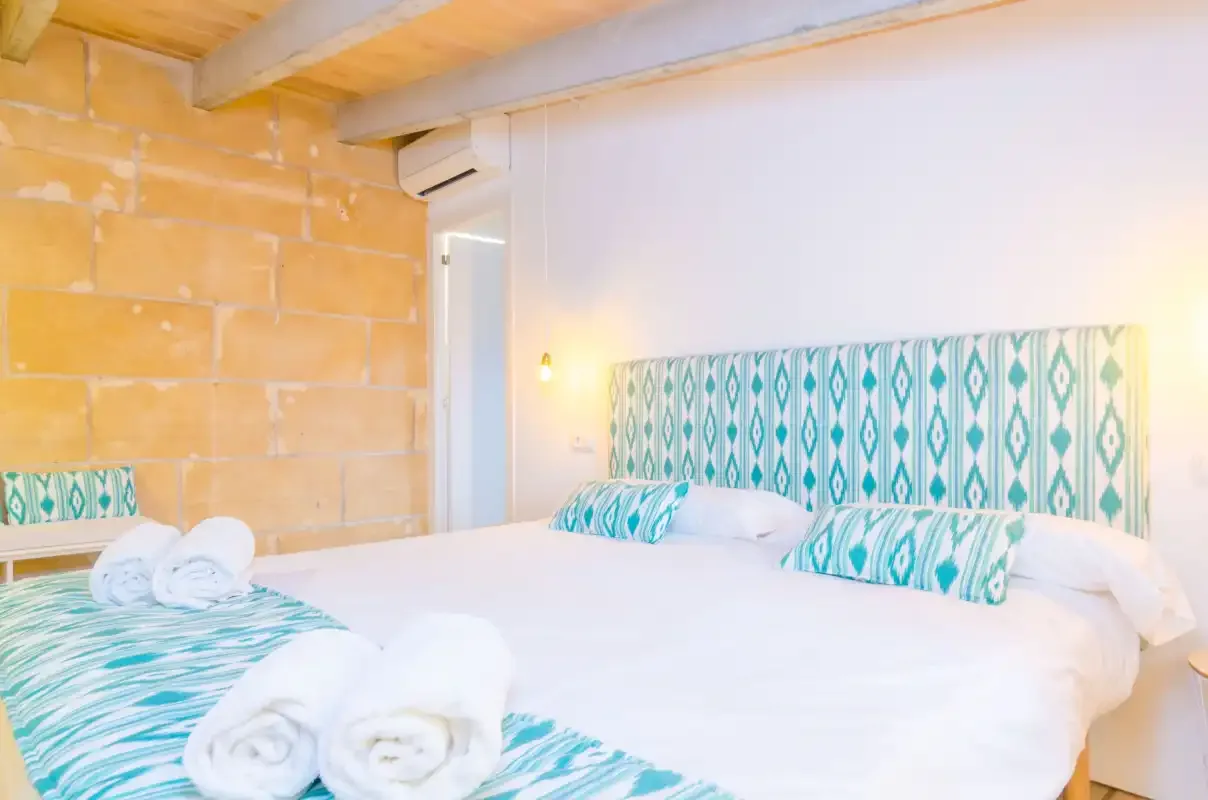 A bright bedroom with a large bed and turquoise patterned bedding.