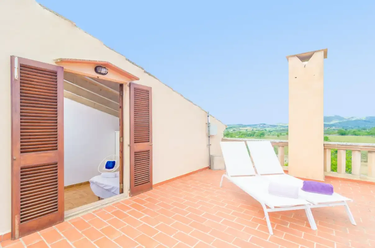 A sunny terrace with lounge seating and an open doorway.