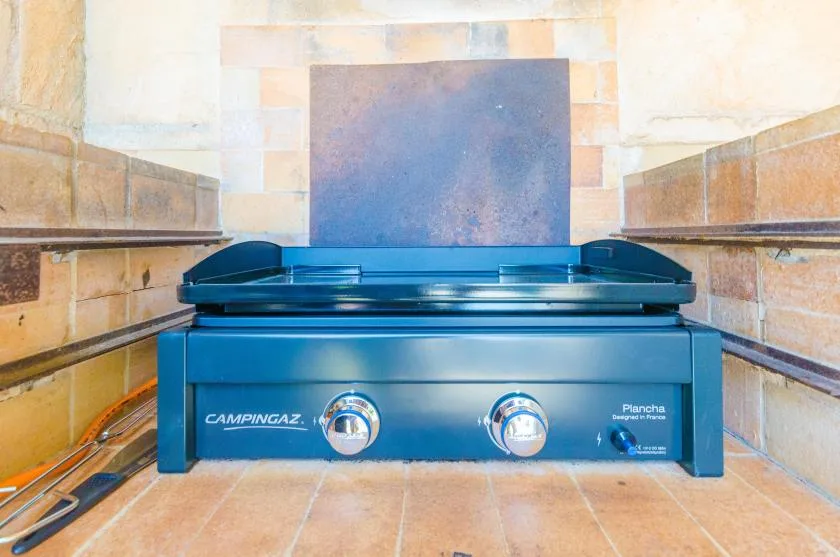 A gas cooktop sits against a tiled backsplash in a kitchen.