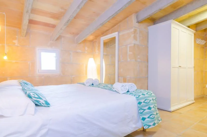 A bedroom with a bed, exposed ceiling beams, and a wardrobe.