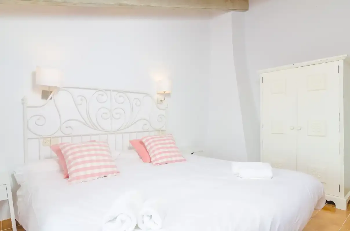 A bright bedroom with a white bed and decorative metal headboard.
