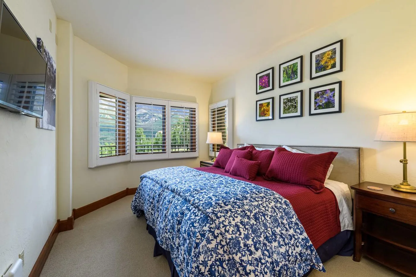 A bedroom with a bed covered in blue-and-white patterned bedding and framed artwork.