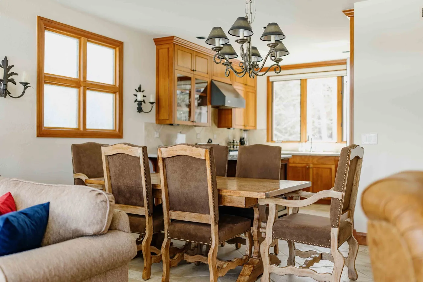 A dining area with a wooden table, upholstered seating, and wood-trimmed windows.