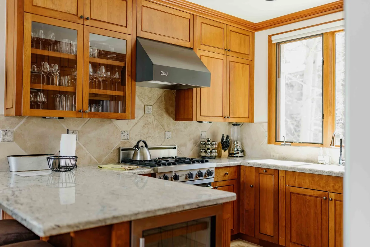 A kitchen with wood cabinets, a cooktop, and light countertops.