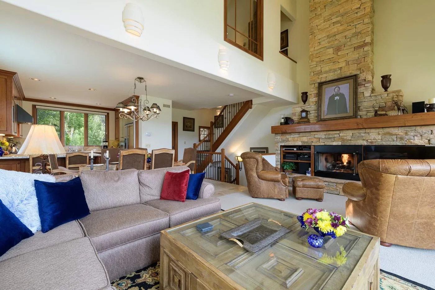 A spacious living room with seating around a glass-topped coffee table and a stone fireplace.
