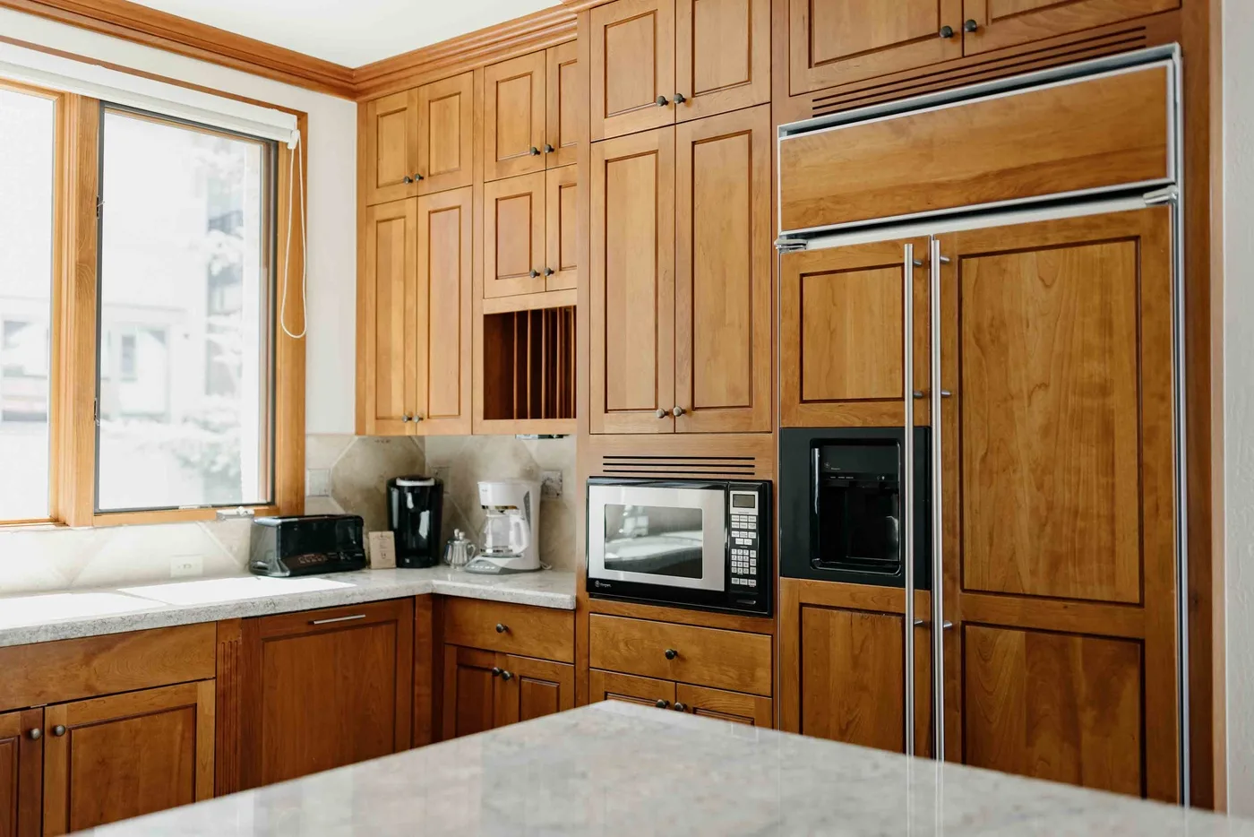 A kitchen with extensive wooden cabinetry, built-in appliances, and a light countertop.