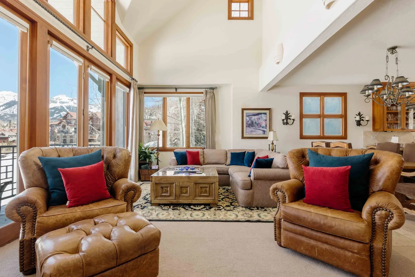 A bright living room with seating arranged around a coffee table and large windows.