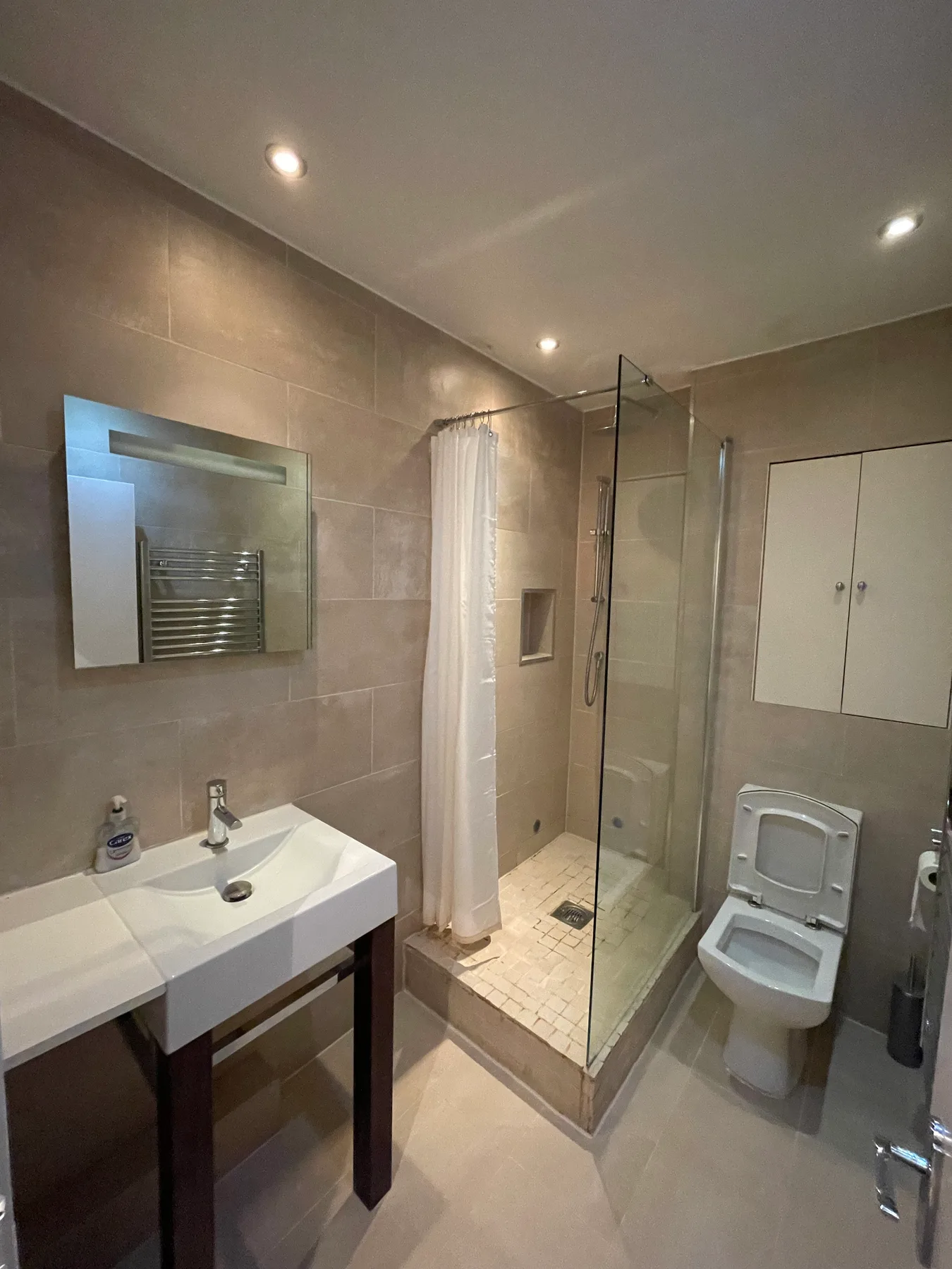 A bathroom with a sink, mirror, shower, and toilet.