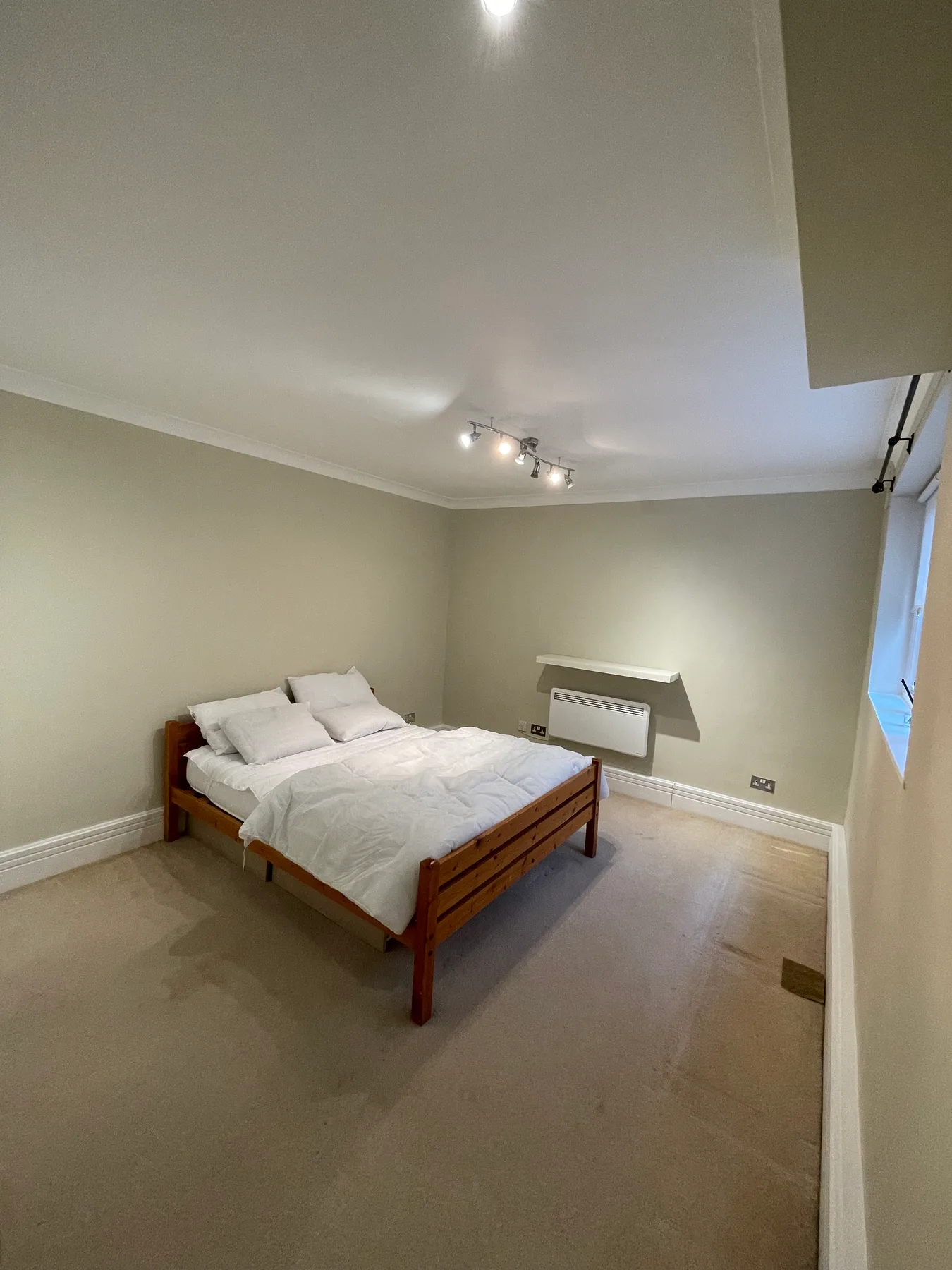 A bedroom with a wooden bed, white bedding, and a small window.