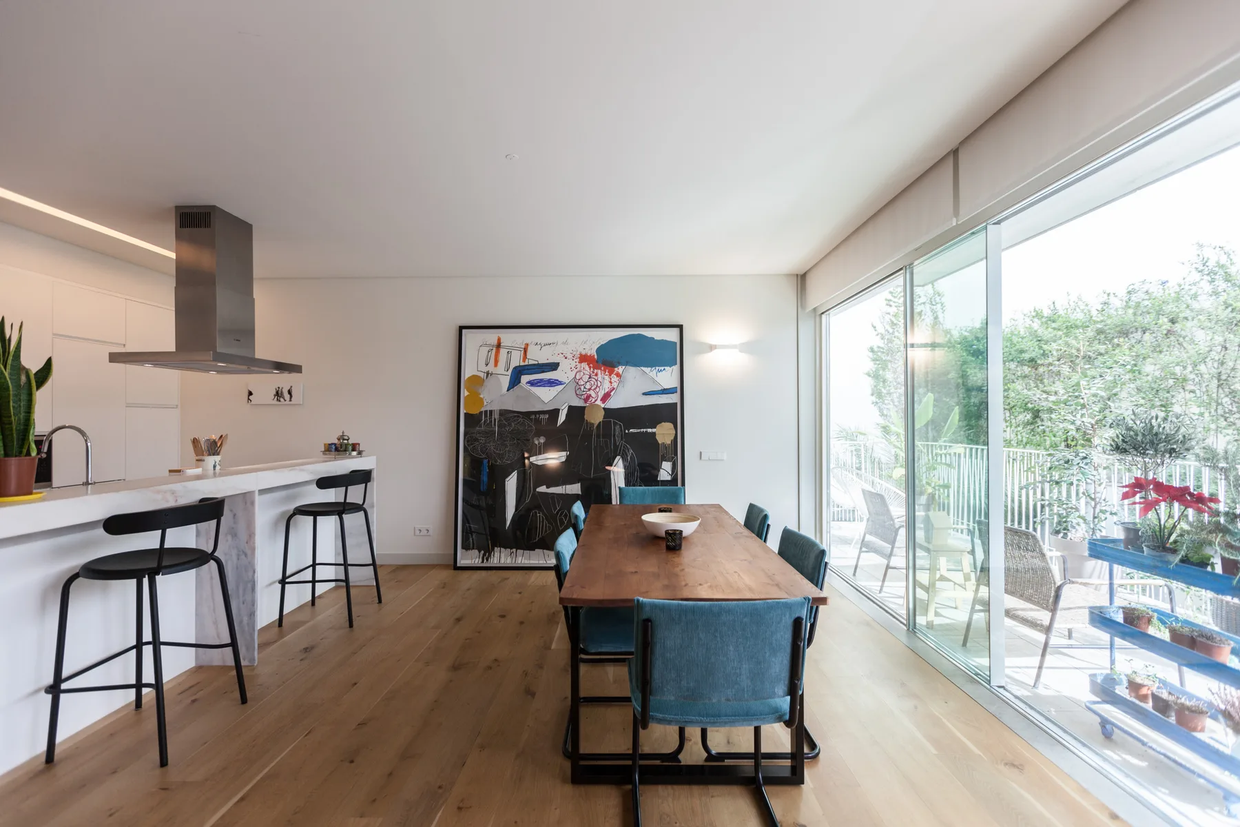 A bright open-plan dining and kitchen area with large glass doors opening onto a balcony.