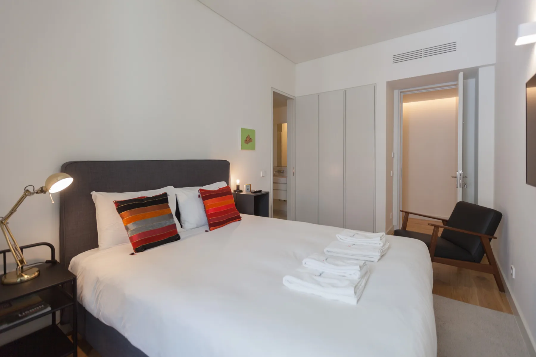 A bedroom with a neatly made bed and colorful striped pillows.