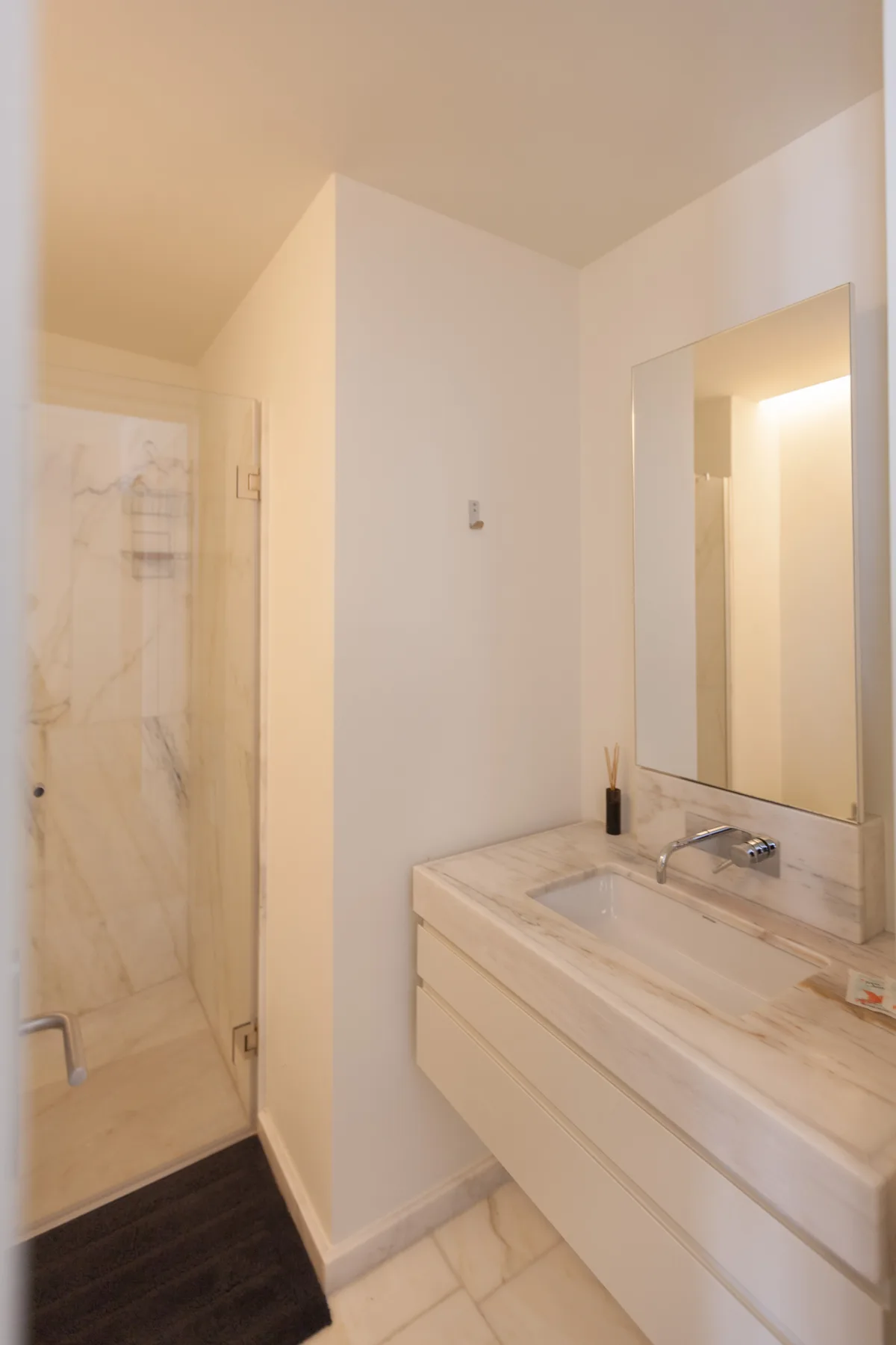 A bathroom with a marble vanity and a glass shower enclosure.