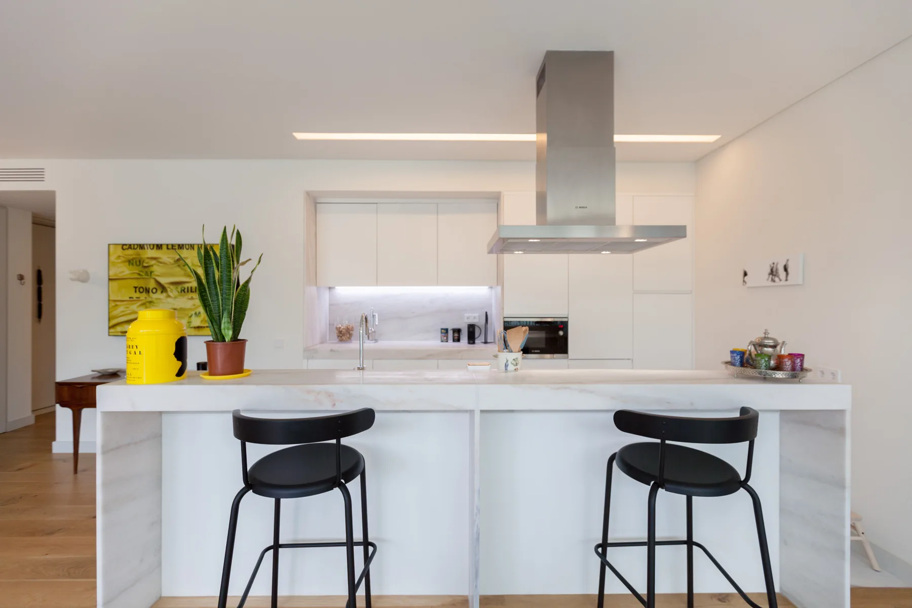 A bright kitchen with a white island and two bar stools.