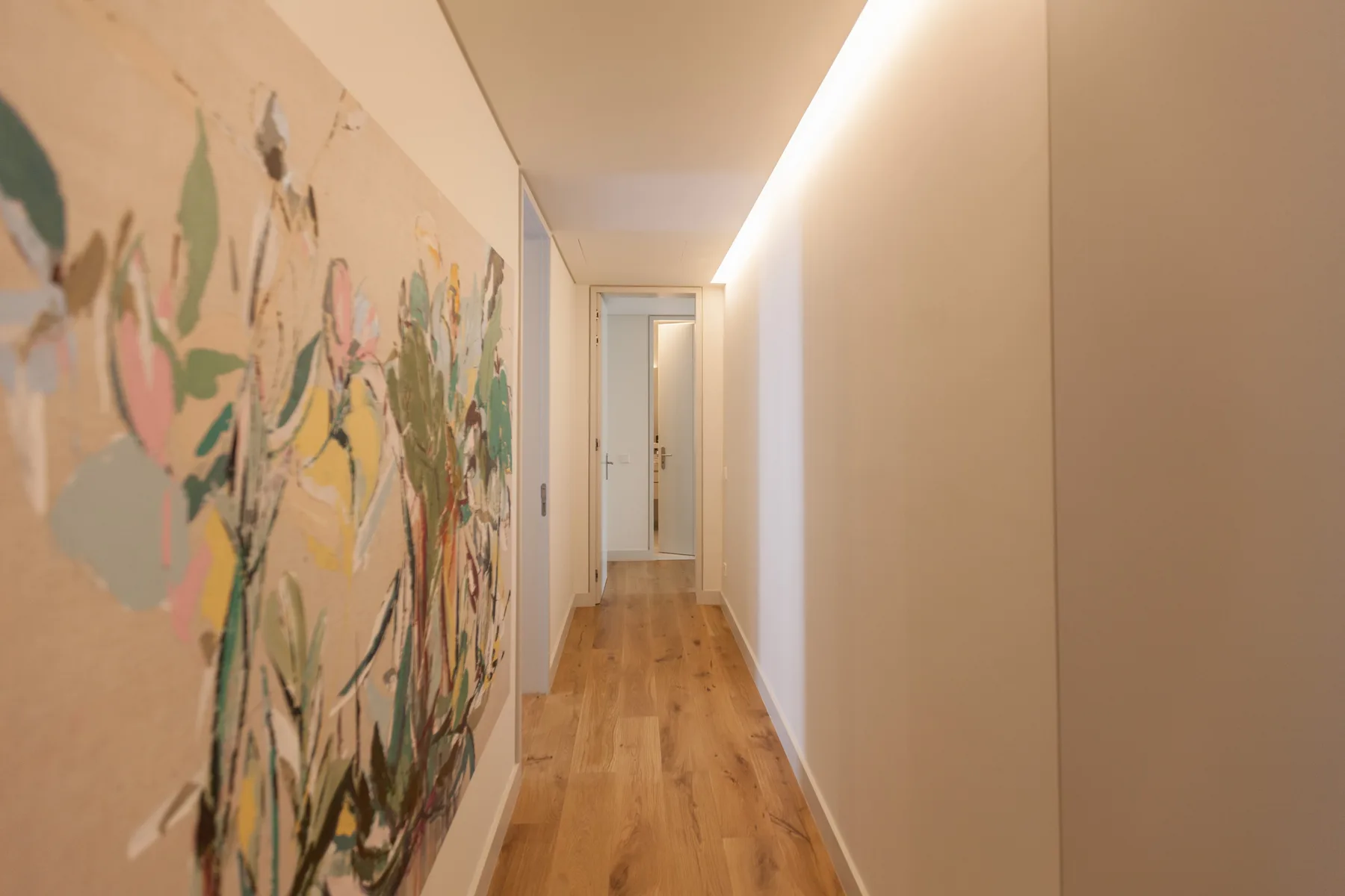 A hallway with wood flooring and a colorful mural along one wall.