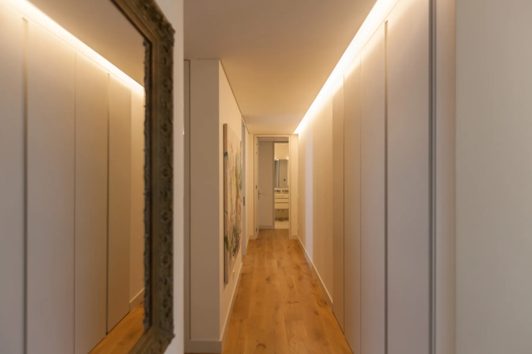 A narrow hallway with wood flooring and built-in cabinets.