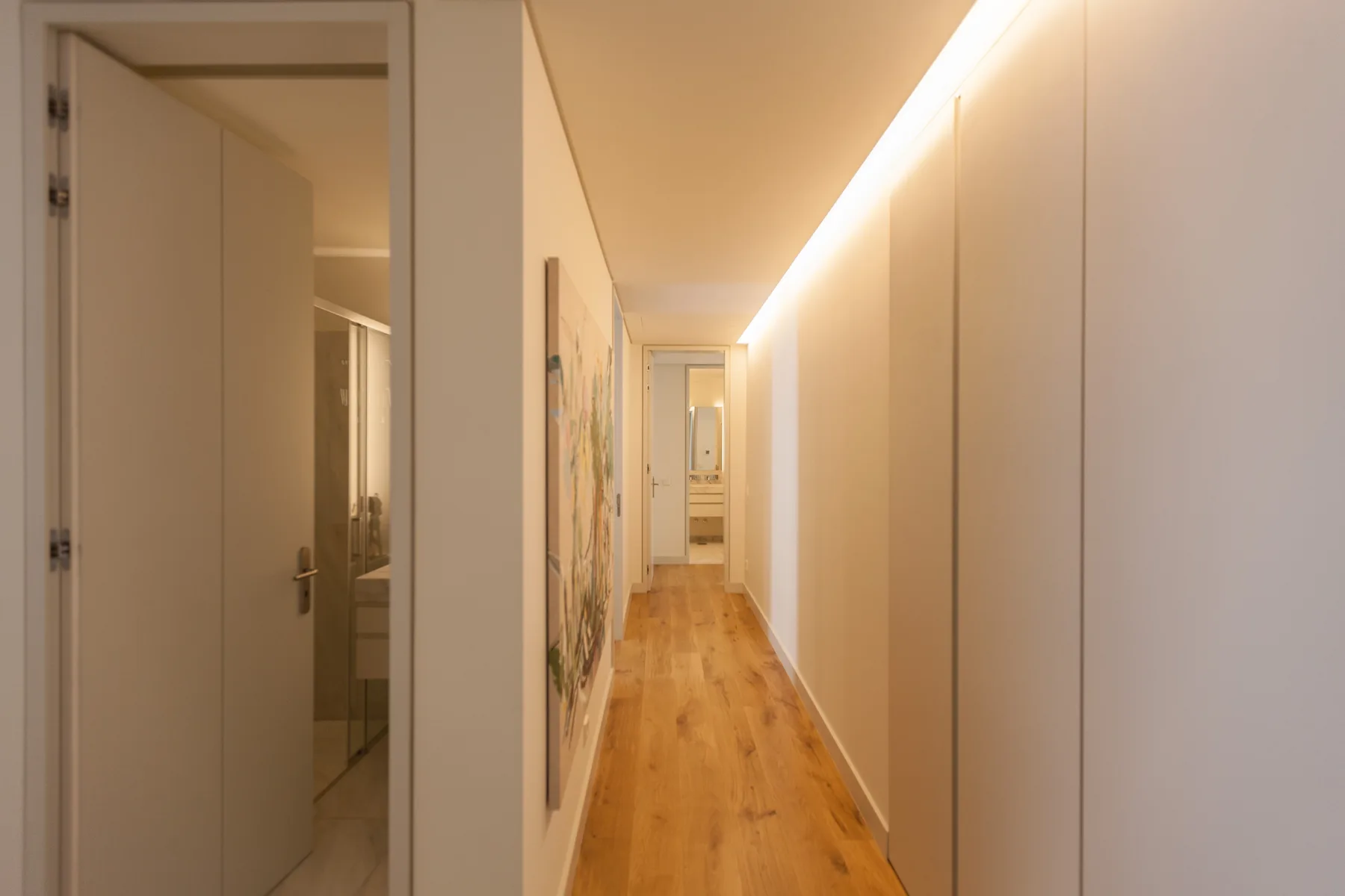 A hallway with wood flooring and a row of built-in cabinets.