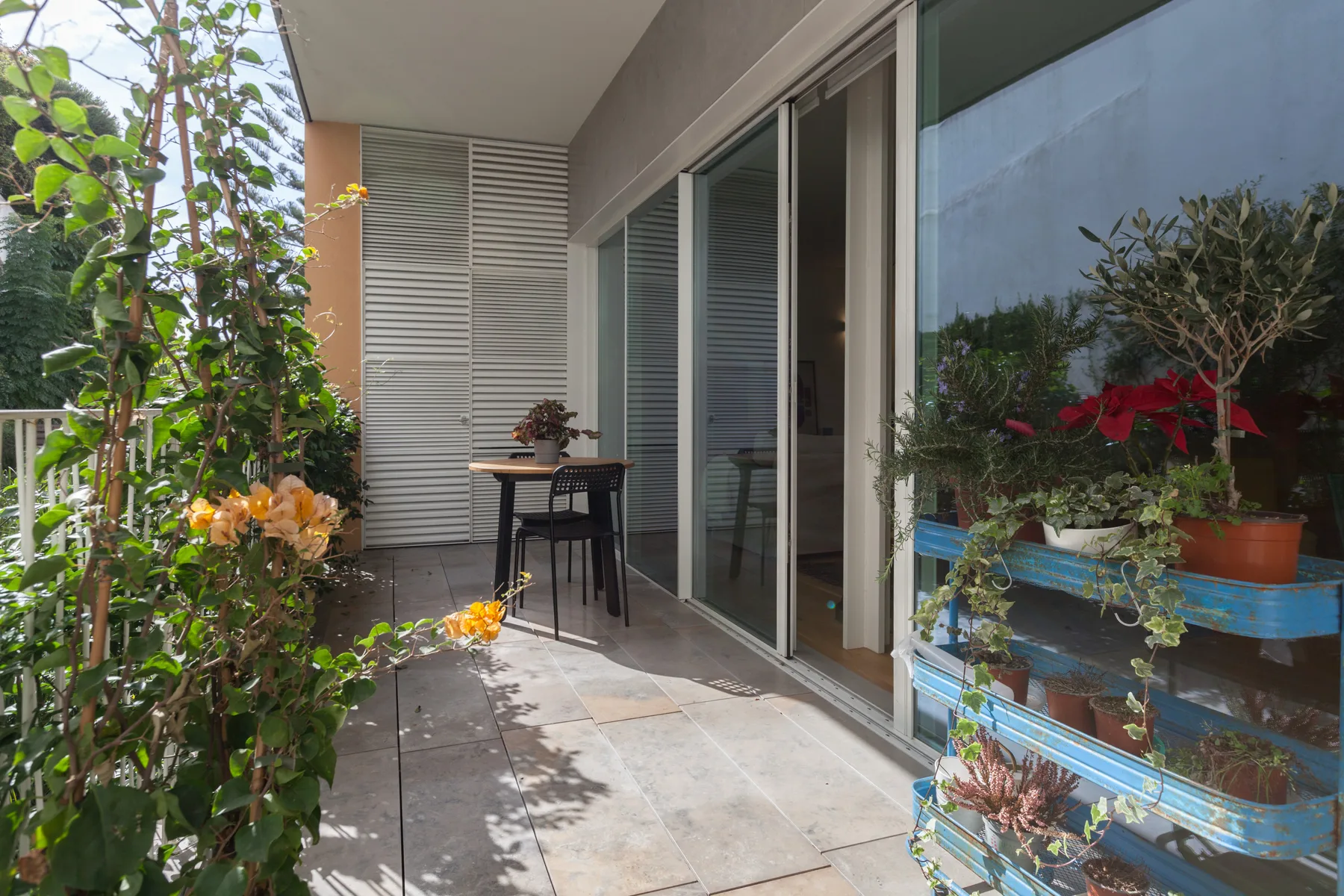 Un patio de balcón con una mesa pequeña y sillas junto a puertas corredizas de vidrio.