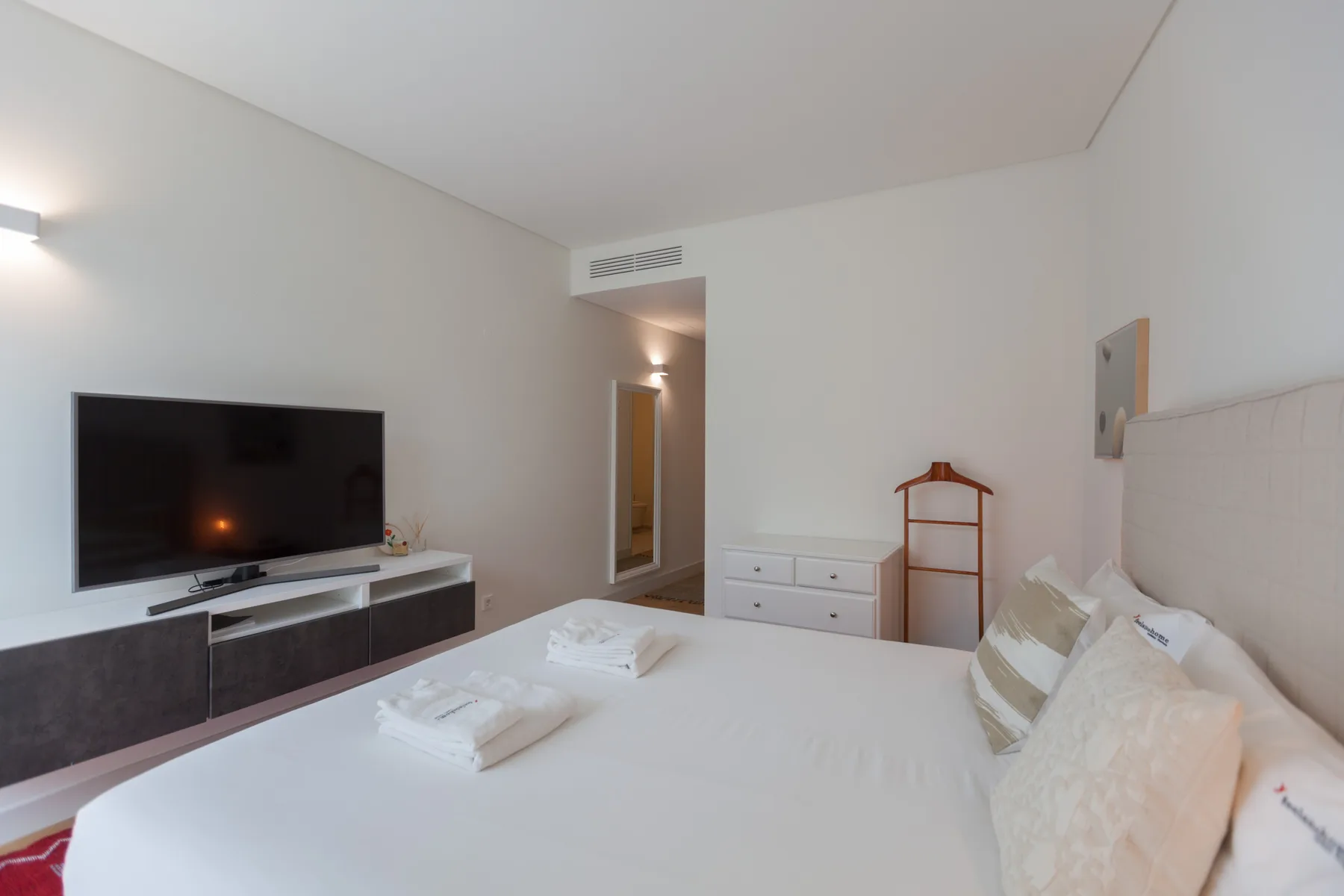 A bedroom with a bed, television, and dresser.