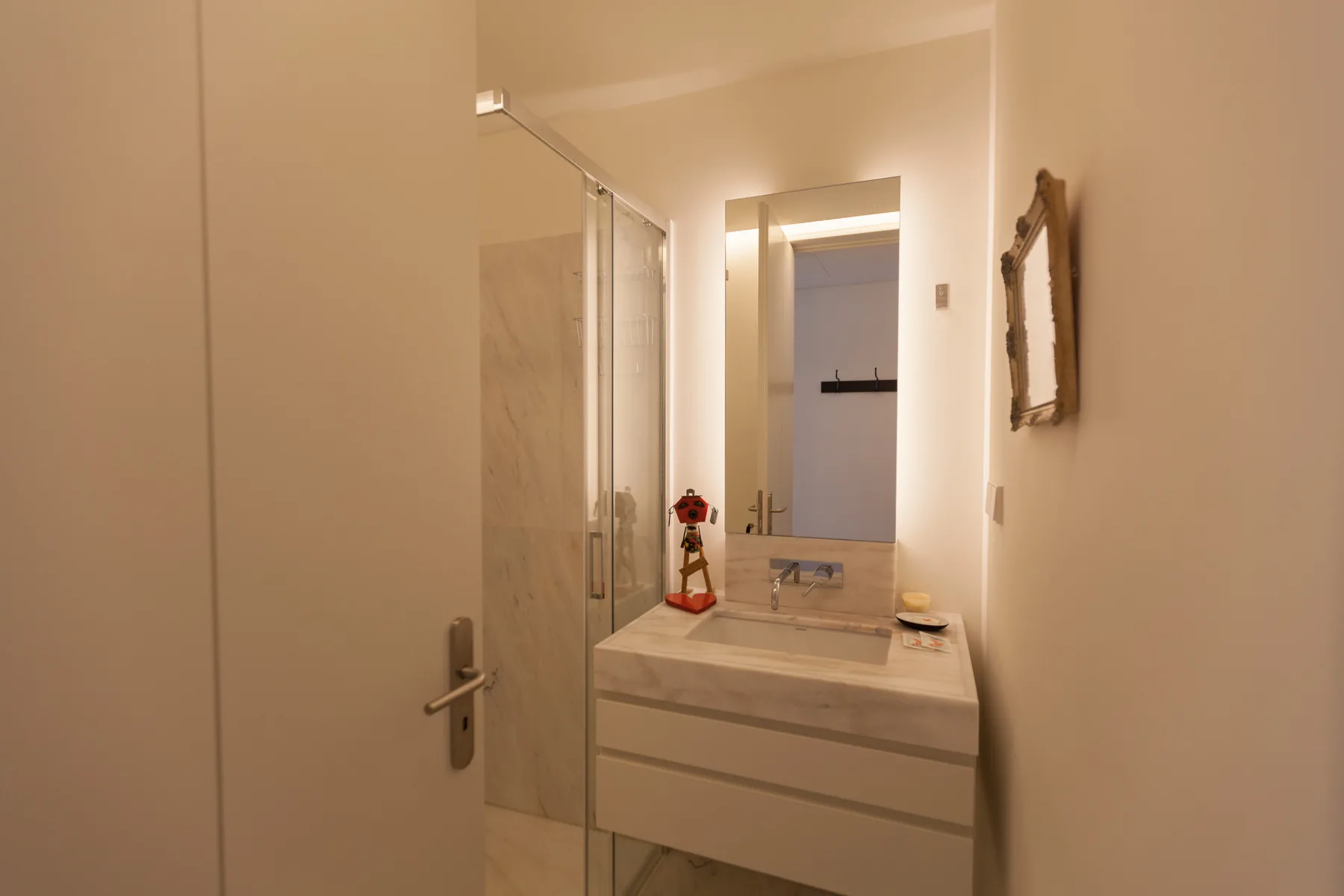 A bathroom vanity with a sink and mirror stands beside a glass shower.