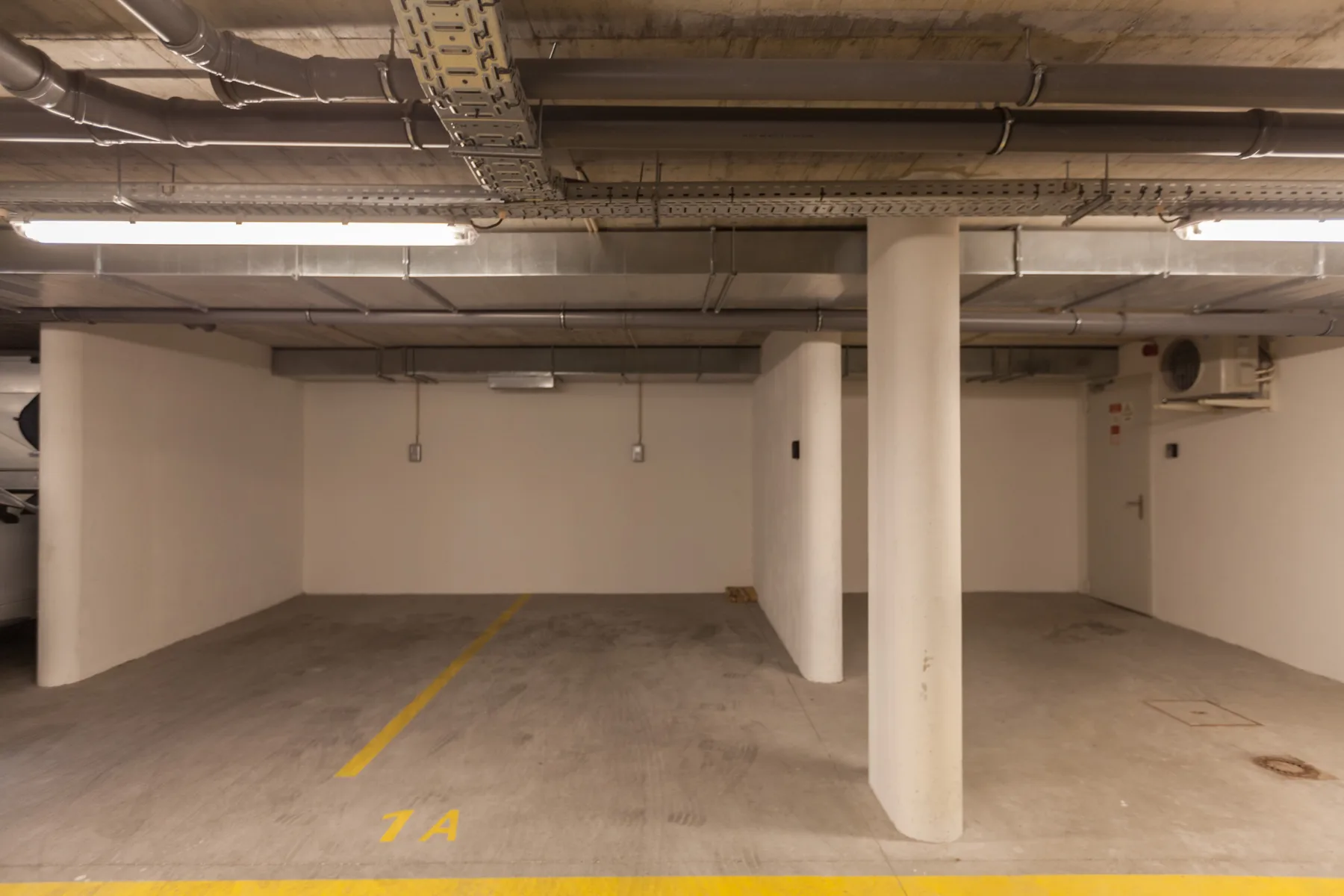 An indoor parking area with empty parking spaces and concrete support columns.