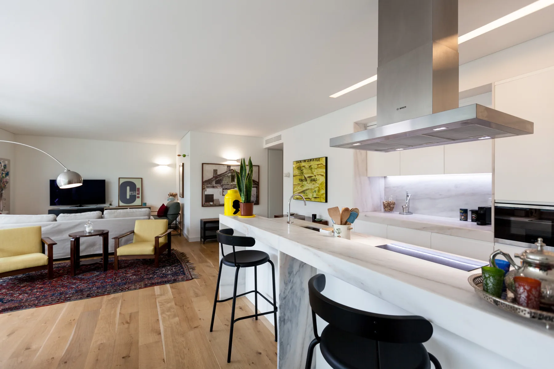 An open-plan living area and kitchen with a long island and bar seating.