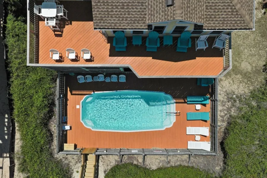 Una vista aérea muestra una piscina junto a una terraza de madera y asientos.