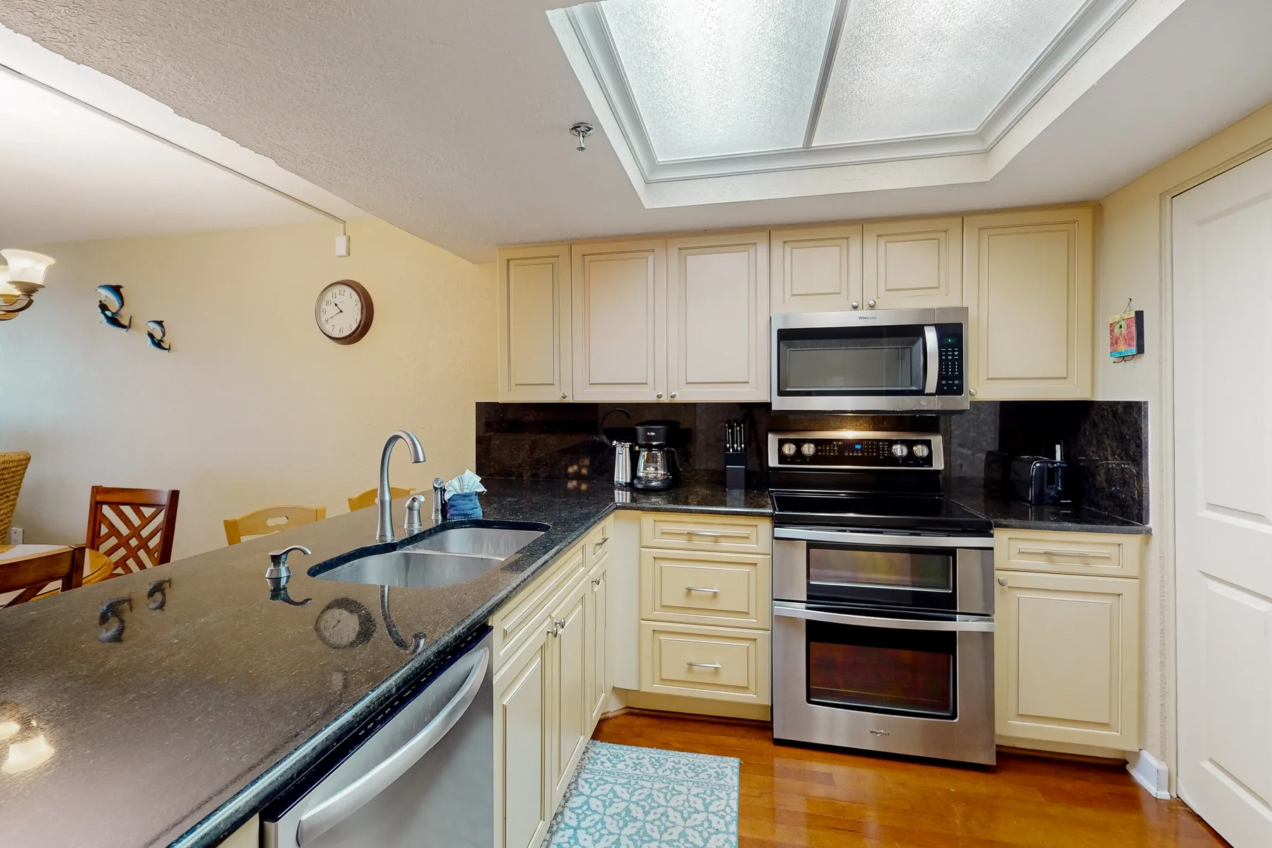 A kitchen with light cabinetry, dark countertops, and a stainless steel range.