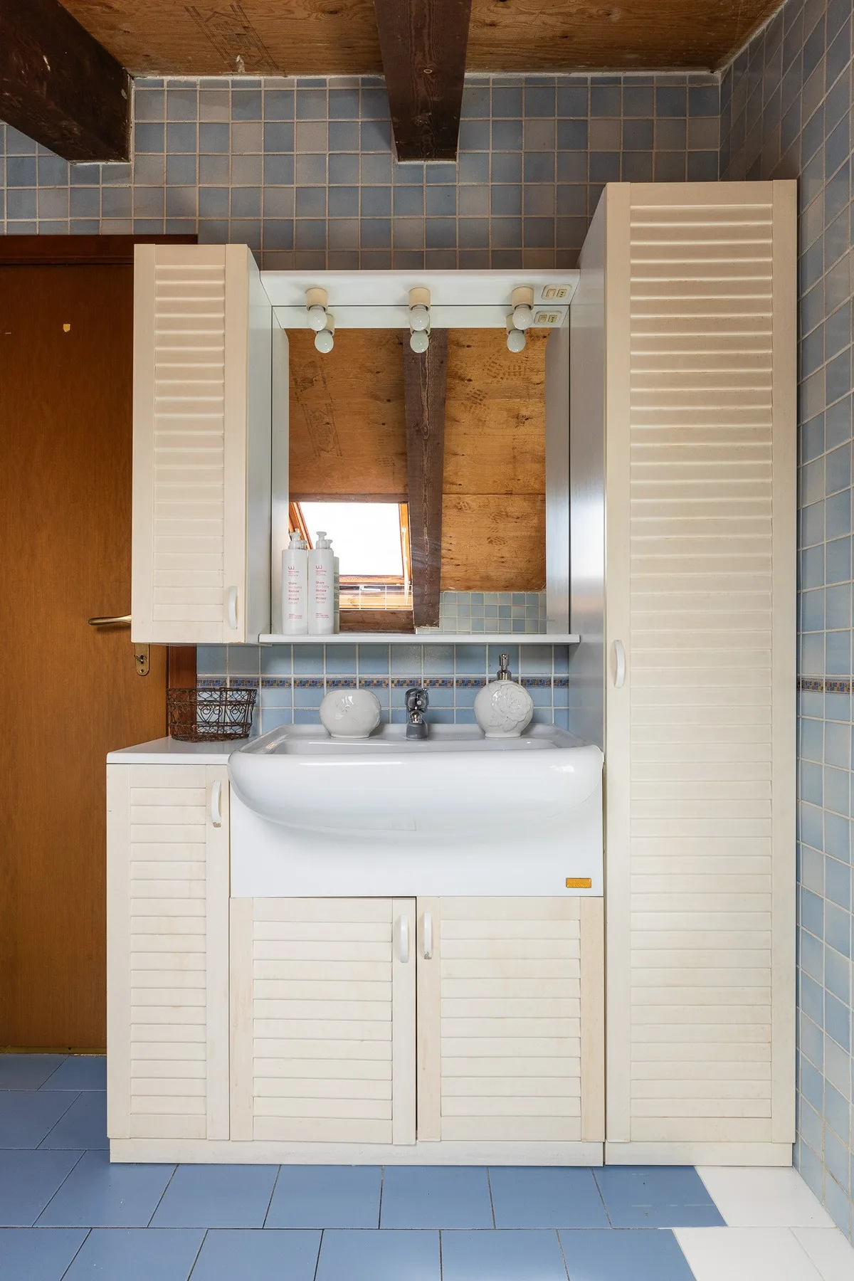 Un baño con azulejos, lavabo y armario con espejo.