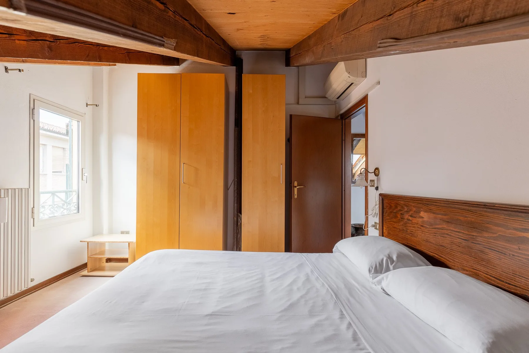Un dormitorio con una cama grande, armarios de madera y una ventana.