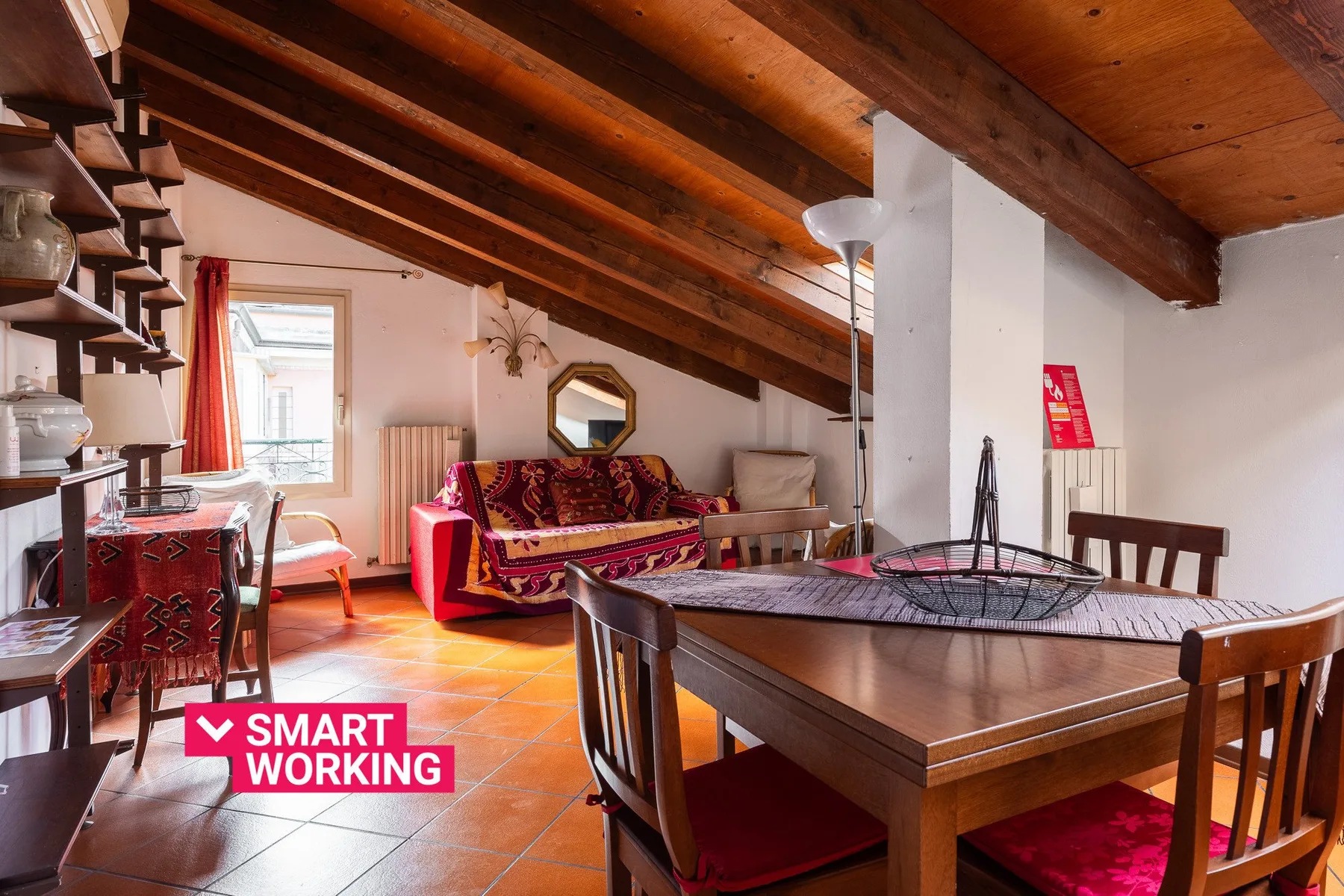 Una sala de estar y comedor con mesa, asientos y vigas de madera a la vista.