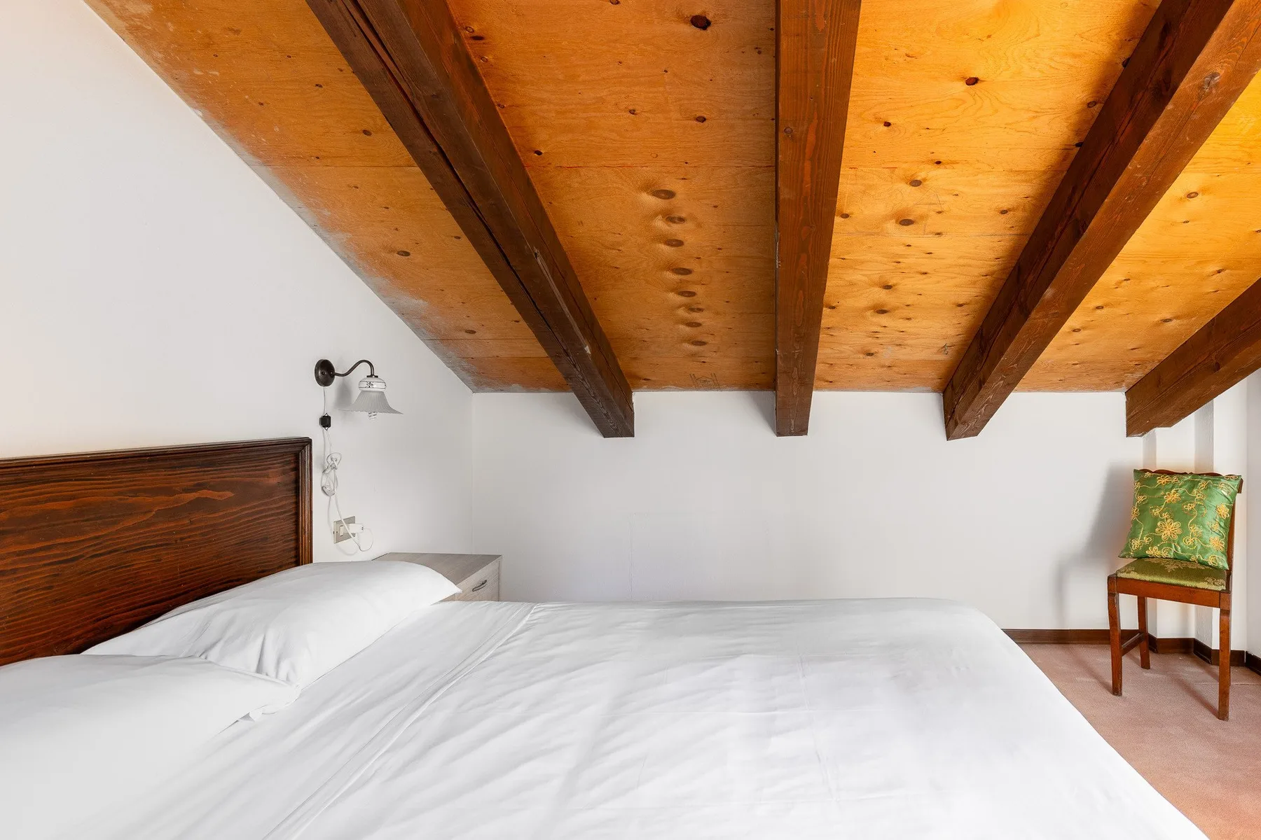 Un dormitorio con una cama grande bajo un techo inclinado de madera.