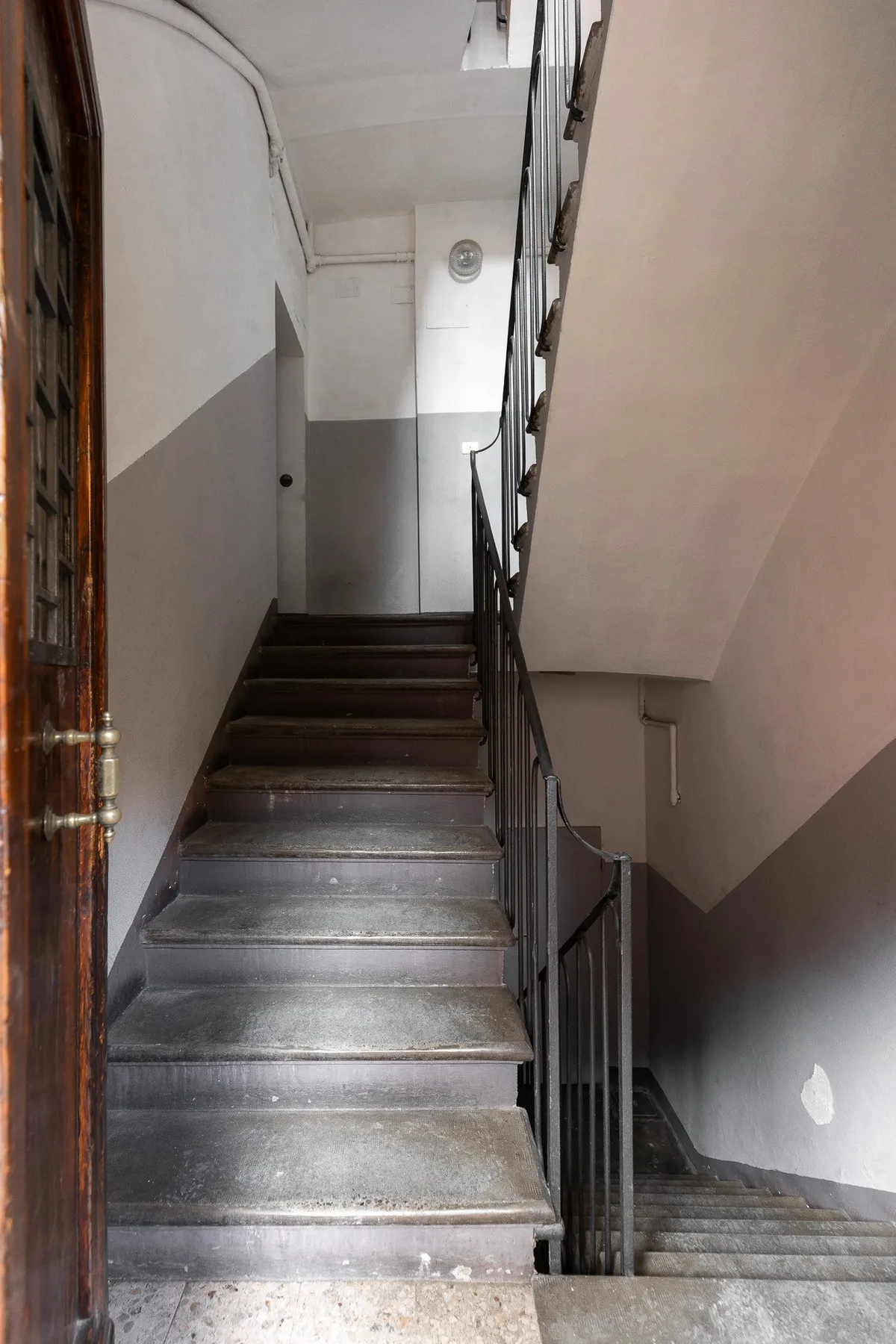 Una escalera interior con barandillas metálicas y paredes pintadas de gris.