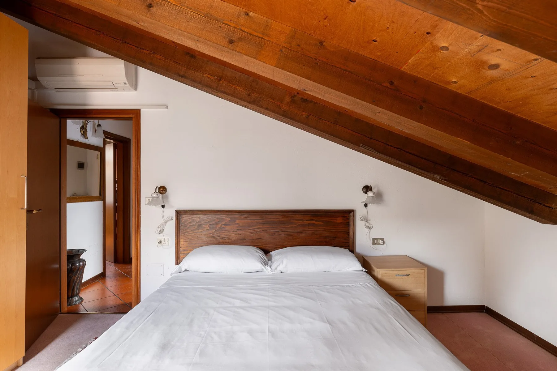Un dormitorio con una cama bajo un techo inclinado de madera.