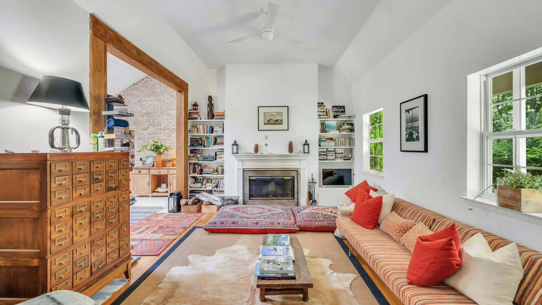 Una sala luminosa con chimenea, estanterías y asientos.