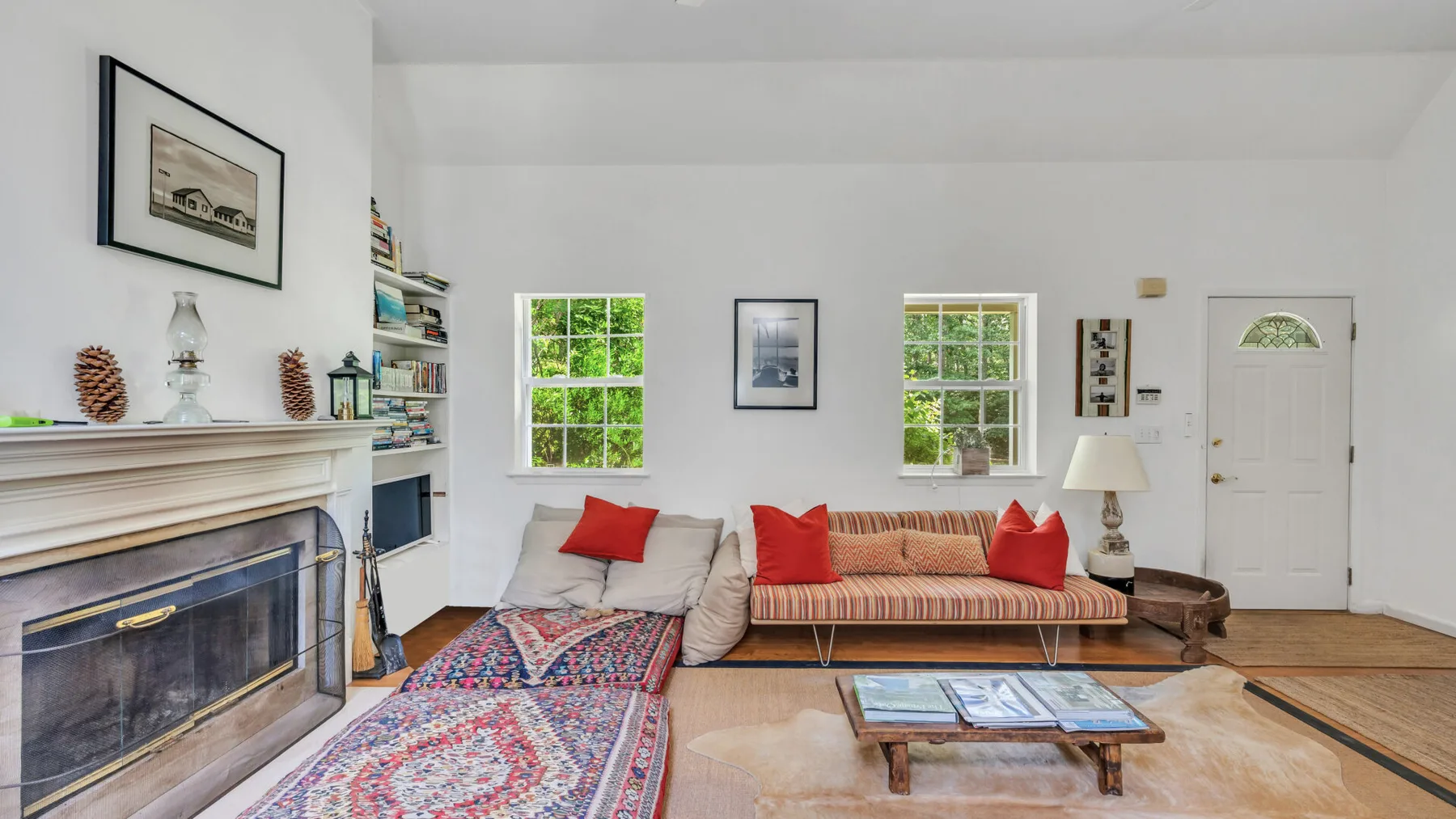 A bright living room with a fireplace, seating, and a patterned rug.