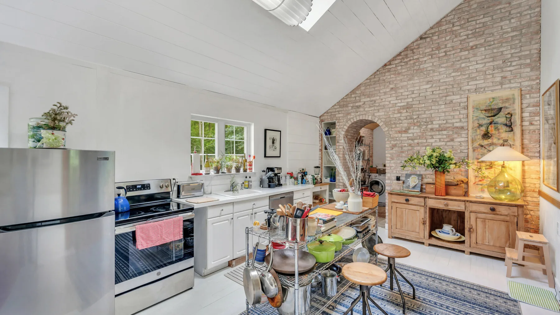 A bright kitchen with a central island and exposed brick wall.