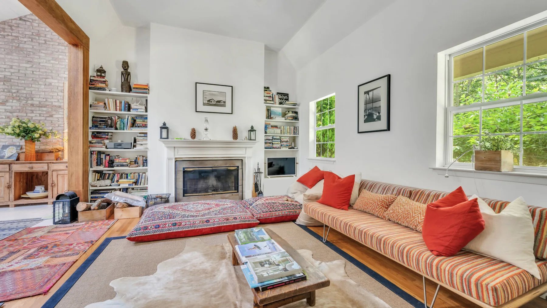 A bright living room with a fireplace, bookshelves, and colorful seating.